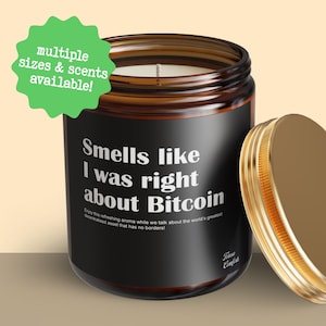 May include: A brown glass jar candle with a gold lid, featuring the text "Smells like I was right about Bitcoin." A green starburst graphic states "multiple sizes & scents available!" The candle has a black label with white text.