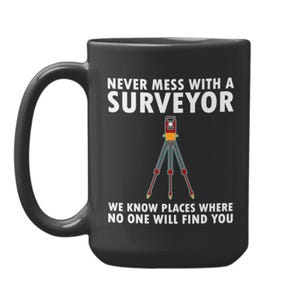 Op de afbeelding: Zwarte keramische mok met de tekst "NEVER MESS WITH A SURVEYOR" en "WE KNOW PLACES WHERE NO ONE WILL FIND YOU." Een landmeetkundig instrument staat in het midden. De mok heeft een groot handvat.