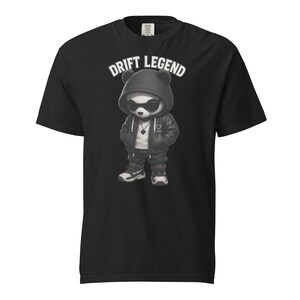 Puede incluir: Camiseta negra con un panda de dibujos animados que lleva gafas de sol y una sudadera con capucha. El panda viste una chaqueta, pantalones y zapatillas negras. El texto "DRIFT LEGEND" está impreso encima del panda.