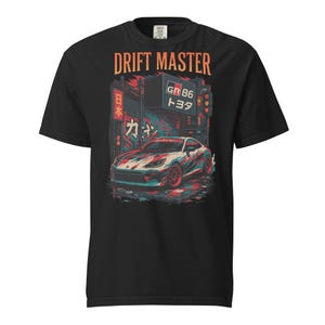 May include: Black t-shirt featuring a graphic of a sports car with red, white, and blue accents, set against a cityscape. The text "DRIFT MASTER" is above the car, with Japanese text and a "GR 86 Toyota" sign.