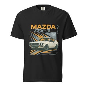 Op de afbeelding: Zwart T-shirt met een afbeelding van een witte Mazda RX-3 auto, oranje en grijze details. De tekst luidt "MAZDA RX-3 JAPAN STREET SPEC". Het T-shirt is gemaakt van een zacht, comfortabel materiaal.