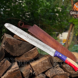 Könnte beinhalten: Ein großes Tranchiermesser aus Damaststahl mit einem Holzgriff mit blauen, weißen und roten Akzenten. Das Messer liegt auf einem Holzstapel mit einer braunen Lederscheide. Das Grill Hunter Knives-Logo ist sichtbar.
