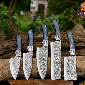 Könnte beinhalten: Ein Set aus fünf Hackmessern mit gemusterten Klingen und blau-grauen Griffen. Die Klingen haben ein dekoratives Blumenmuster. Die Messer sind auf einer Holzoberfläche angeordnet. Das Logo "Grill Hunter Knives" ist sichtbar.
