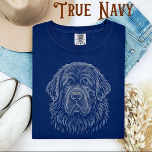 May include: True navy blue t-shirt featuring a detailed white illustration of a dog's face. The shirt has a crew neck and a tag that reads "Comfort Colors". The words "TRUE NAVY" are printed at the top of the image.