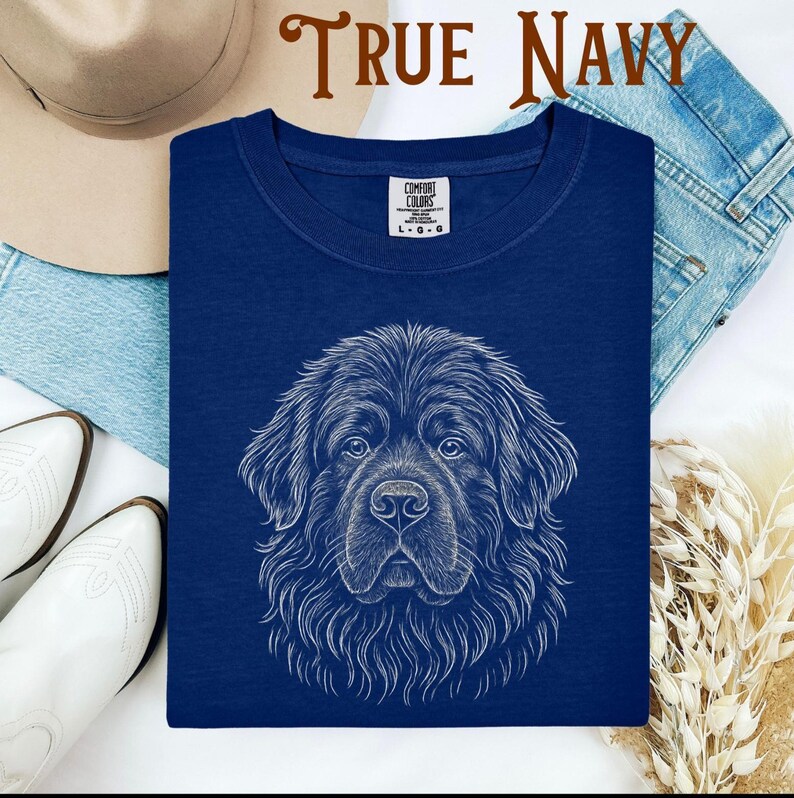 May include: True navy blue t-shirt featuring a detailed white illustration of a dog's face. The shirt has a crew neck and a tag that reads "Comfort Colors". The words "TRUE NAVY" are printed at the top of the image.