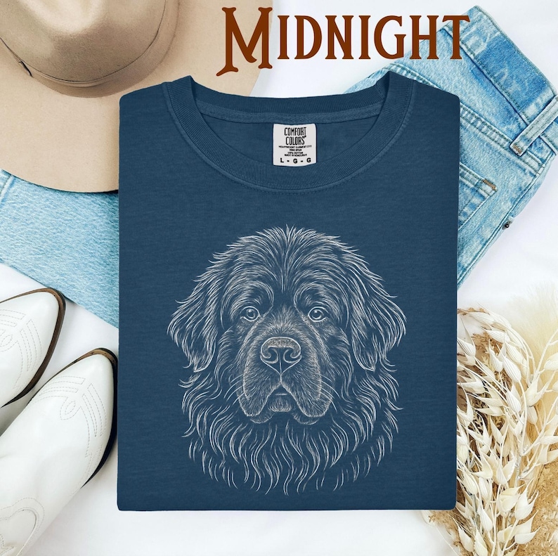 May include: A navy blue Comfort Colors t-shirt featuring a detailed white line drawing of a dog's face. The word "MIDNIGHT" is printed in a brown font at the top. The shirt is surrounded by a hat, jeans, and boots.