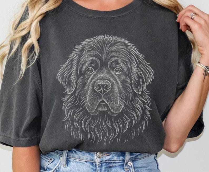 May include: Dark gray t-shirt featuring a detailed, white line drawing of a Newfoundland dog's face. The dog's fur is depicted with intricate lines, creating a textured effect. The shirt has a classic crew neck and short sleeves.