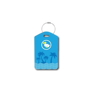 Puede incluir: Etiqueta de equipaje azul con un dodo blanco y palmeras sobre un fondo azul. La etiqueta tiene un lazo plateado para sujetar al equipaje.