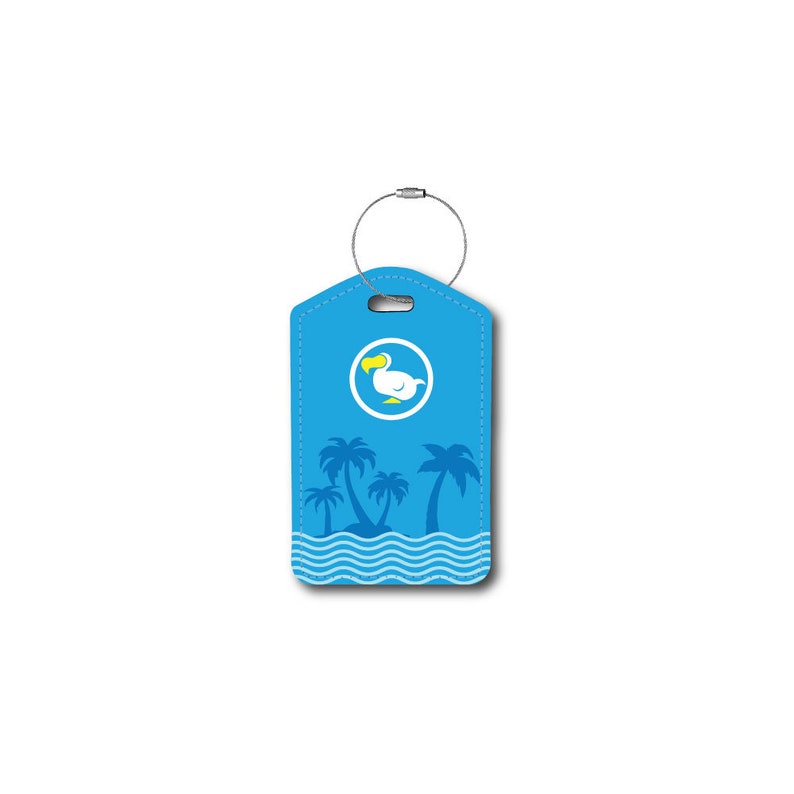Puede incluir: Etiqueta de equipaje azul con un dodo blanco y palmeras sobre un fondo azul. La etiqueta tiene un lazo plateado para sujetar al equipaje.