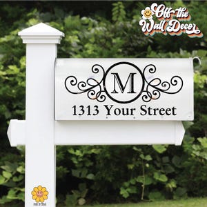 May include: White mailbox with black decorative scrollwork, a large letter "M" inside a circle, and the address "1313 Your Street." The mailbox is mounted on a white post with a daisy sticker.