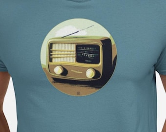 May include: Teal t-shirt featuring a circular graphic of a vintage radio. The radio illustration is in shades of yellow, brown, and black, set against a light green and brown background. The shirt is a solid teal color.