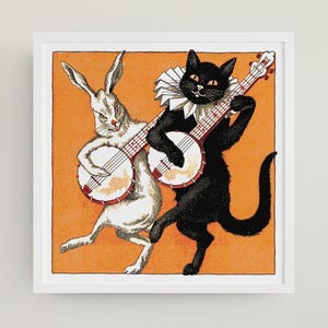Puede incluir: Una impresión enmarcada que presenta un conejo blanco y un gato negro tocando el banjo sobre un fondo naranja. El conejo tiene orejas rosas y el gato lleva un cuello con volantes. La obra de arte tiene un estilo vintage y caprichoso.