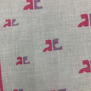 Peut inclure: Un textile gris clair avec un motif r&eacute;p&eacute;titif de formes de lettres stylis&eacute;es bicolores magenta et violet. Les bords sont bord&eacute;s d'une bande magenta. Le tissu a un aspect subtil et textur&eacute;.