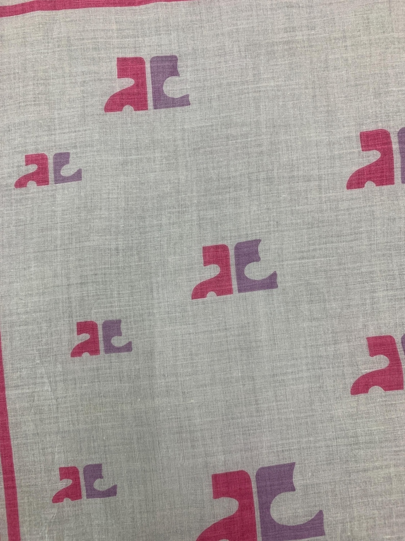 Peut inclure: Un textile gris clair avec un motif r&eacute;p&eacute;titif de formes de lettres stylis&eacute;es bicolores magenta et violet. Les bords sont bord&eacute;s d'une bande magenta. Le tissu a un aspect subtil et textur&eacute;.