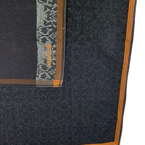 Puede incluir: Un pa&ntilde;uelo gris oscuro con un dise&ntilde;o floral. El pa&ntilde;uelo tiene un borde con una franja marr&oacute;n y naranja. La esquina del pa&ntilde;uelo tiene un dise&ntilde;o gris y negro con el texto "Skevi Vintige" en naranja.
