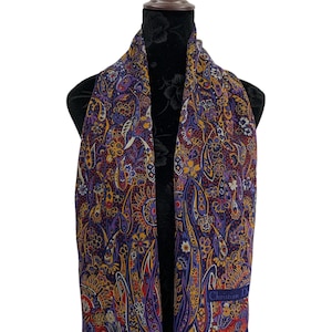May include: A paisley patterned scarf in shades of purple, yellow, red, and blue. The scarf is draped over a black mannequin. The scarf has a dark blue border and the text "Christian Dior" is visible.