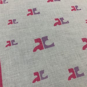 Peut inclure: Un textile gris clair avec un motif r&eacute;p&eacute;t&eacute; de formes stylis&eacute;es magenta et violettes. Les bords sont bord&eacute;s d'une bordure magenta. Le tissu a un aspect l&eacute;g&egrave;rement textur&eacute;.