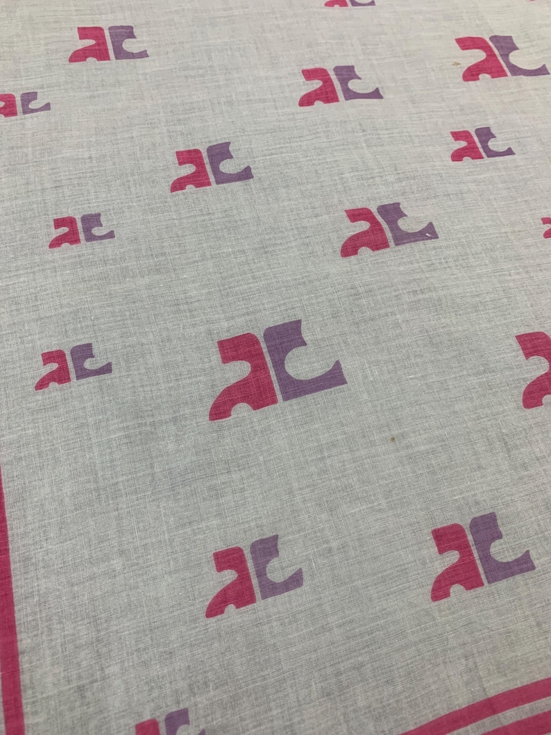 Peut inclure: Un textile gris clair avec un motif r&eacute;p&eacute;t&eacute; de formes stylis&eacute;es magenta et violettes. Les bords sont bord&eacute;s d'une bordure magenta. Le tissu a un aspect l&eacute;g&egrave;rement textur&eacute;.