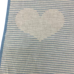 K&ouml;nnte beinhalten: Ein hellblau-wei&szlig; gestreifter Stoff mit einem gro&szlig;en Herzdesign. Das Herz ist wei&szlig; und die Streifen sind hellblau. Die R&auml;nder des Textils sind mit einem durchgehenden Hellblau eingefasst.
