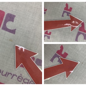 Peut inclure: Un textile gris clair avec un motif r&eacute;p&eacute;t&eacute; d'un logo stylis&eacute; en rose et violet. Le mot "courr&egrave;ges" est imprim&eacute; en rose. Une fl&egrave;che rouge est plac&eacute;e sur le textile.