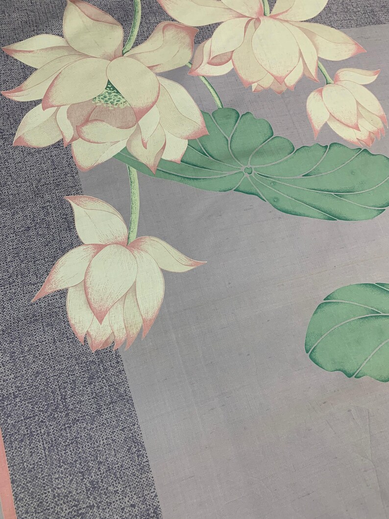 May include: A floral textile featuring a watercolor design of lotus flowers and leaves. The flowers are a soft cream color with pink edges, and the leaves are green. The background has a textured gray and light purple color scheme.