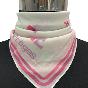 Peut inclure: Foulard blanc avec un motif rose et le mot "arr&egrave;ges" imprim&eacute;. Le foulard, de forme triangulaire, est pli&eacute; autour d'une forme noire. Il pr&eacute;sente des rayures roses sur les bords.