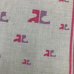 Peut inclure: Un textile gris clair avec un motif r&eacute;p&eacute;t&eacute; de lettres "AC" stylis&eacute;es dans des tons de rose et de violet. La bordure pr&eacute;sente une rayure rose. Le tissu semble l&eacute;ger.