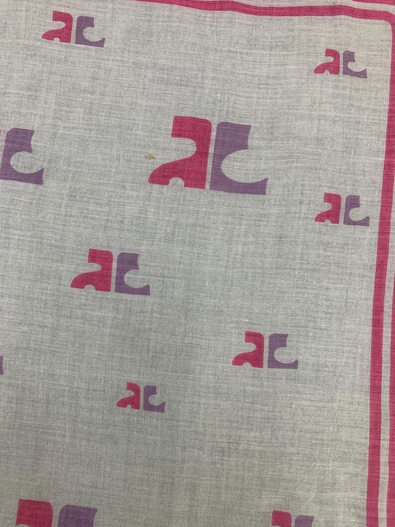 Peut inclure: Un textile gris clair avec un motif r&eacute;p&eacute;t&eacute; de lettres "AC" stylis&eacute;es dans des tons de rose et de violet. La bordure pr&eacute;sente une rayure rose. Le tissu semble l&eacute;ger.