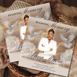 May include: Two memorial cards with the text "In Loving Memory" and a photo of a woman in a white suit. The cards feature doves, roses, and the name "Anna Marrie" with dates and location details. The background is a soft, cloudy design.