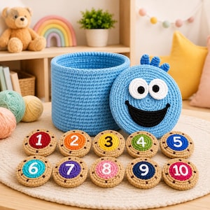 May include: A light blue crochet storage basket with a matching lid featuring a cartoon face with large white eyes and a black smile. Ten round crochet number tokens, numbered one through ten in various colors, are arranged in front.