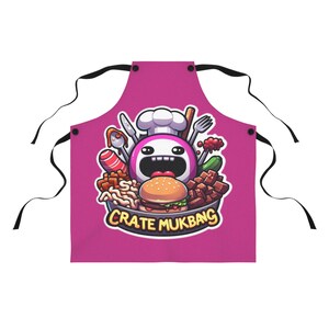 May include: A magenta apron with a cartoon chef design surrounded by food like a burger, sausage, and vegetables. The apron has black ties and the text "CRATE MUKBANG" in a yellow banner.