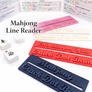 May include: A collection of Mahjong Line Readers in various colors, including pink, white, red, and navy blue. Each reader has the words "Crack Dot Bam" and "Mahjong" in a stylized font. Also included are Mahjong tiles.