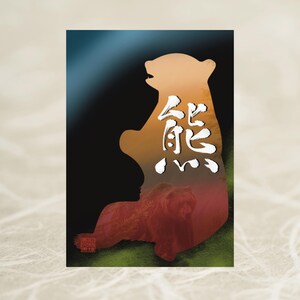 以下が含まれることがあります： 日本の文字が入ったクマのシルエットが特徴の長方形のアートプリント。クマは木々やクマの風景で満たされています。背景は黒から青、オレンジへと変化します。