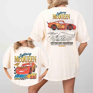 May include: Cream-colored t-shirt featuring Lightning McQueen graphics. The front design includes the text "Lightning McQueen", the number "95", and the phrase "Think Fast". The back displays a larger design with the text "Lightning McQueen", the number "95", and "Piston Cup Champion".