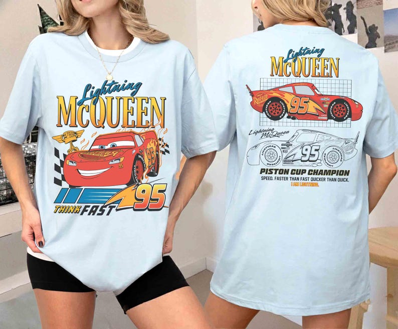 May include: Light blue t-shirt featuring Lightning McQueen from the Cars movie. The front graphic shows McQueen with the number 95 and the text "Think Fast". The back displays McQueen and the text "Piston Cup Champion".