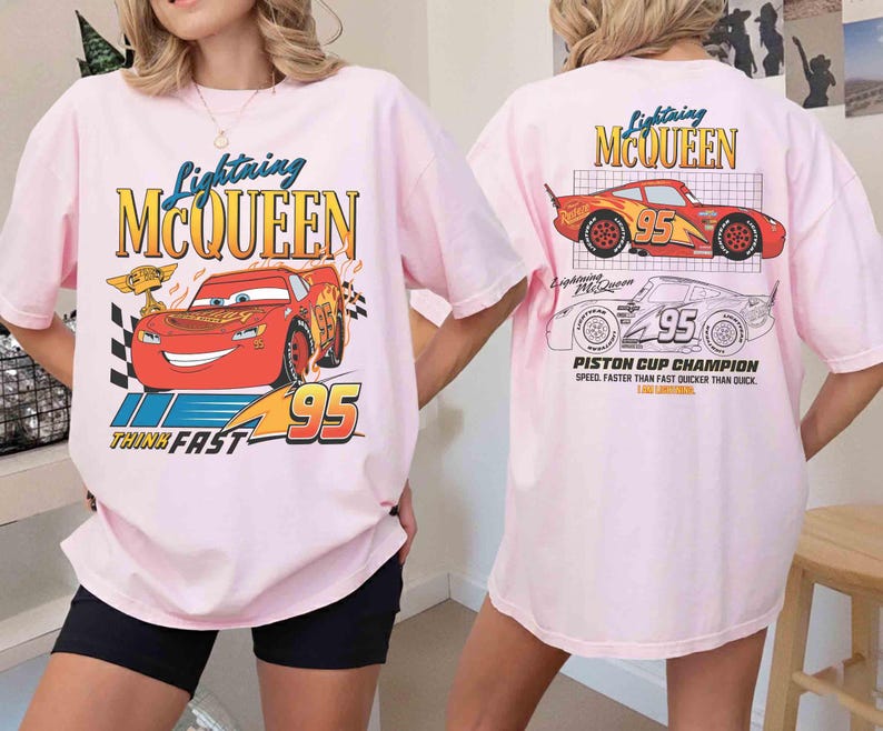 May include: Pink t-shirt featuring Lightning McQueen from the Cars movie. The front graphic shows McQueen with the text "Lightning McQueen" and "95". The back of the shirt has a graphic of McQueen and the text "Piston Cup Champion".