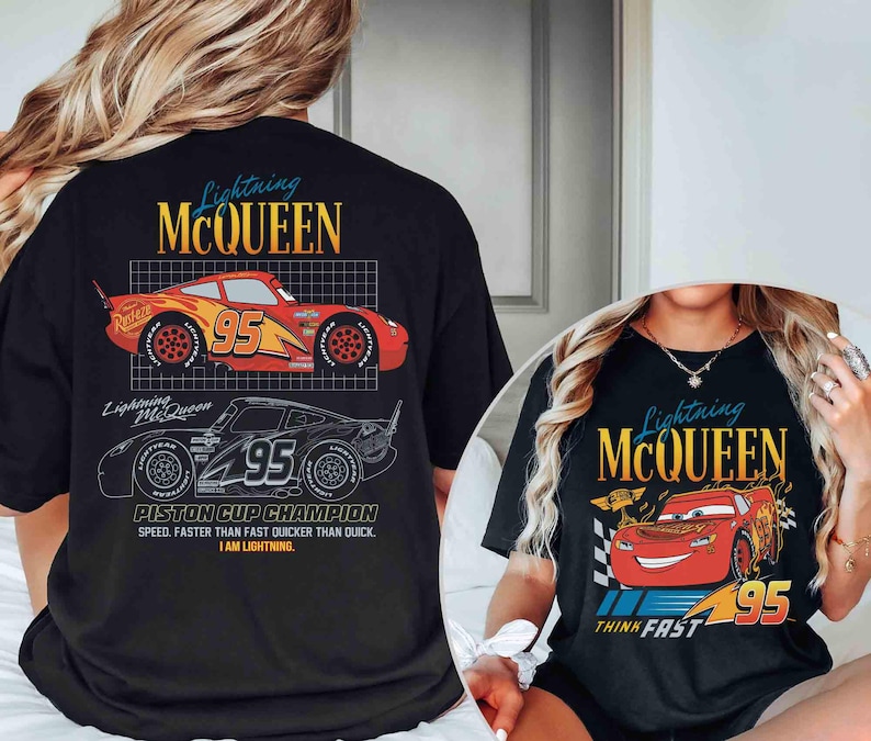 May include: Black t-shirts featuring Lightning McQueen from the Cars movie. The shirts display the text "Lightning McQueen" in a stylized font, along with the number "95" and a graphic of the race car. One shirt also has the text "Piston Cup Champion".