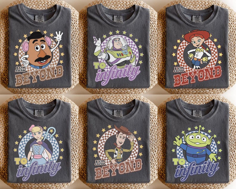 May include: Six charcoal gray t-shirts featuring Toy Story characters. Each shirt displays a circular graphic with a checkered border and stars. Characters include Mr. Potato Head, Buzz Lightyear, Jessie, Bo Peep, Woody, and an Alien with text.
