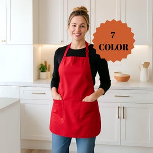 May include: A bright red apron with two large front pockets. The apron is being worn in a kitchen setting. The text "7 COLOR" is displayed on a circular orange background. The apron is a solid color.