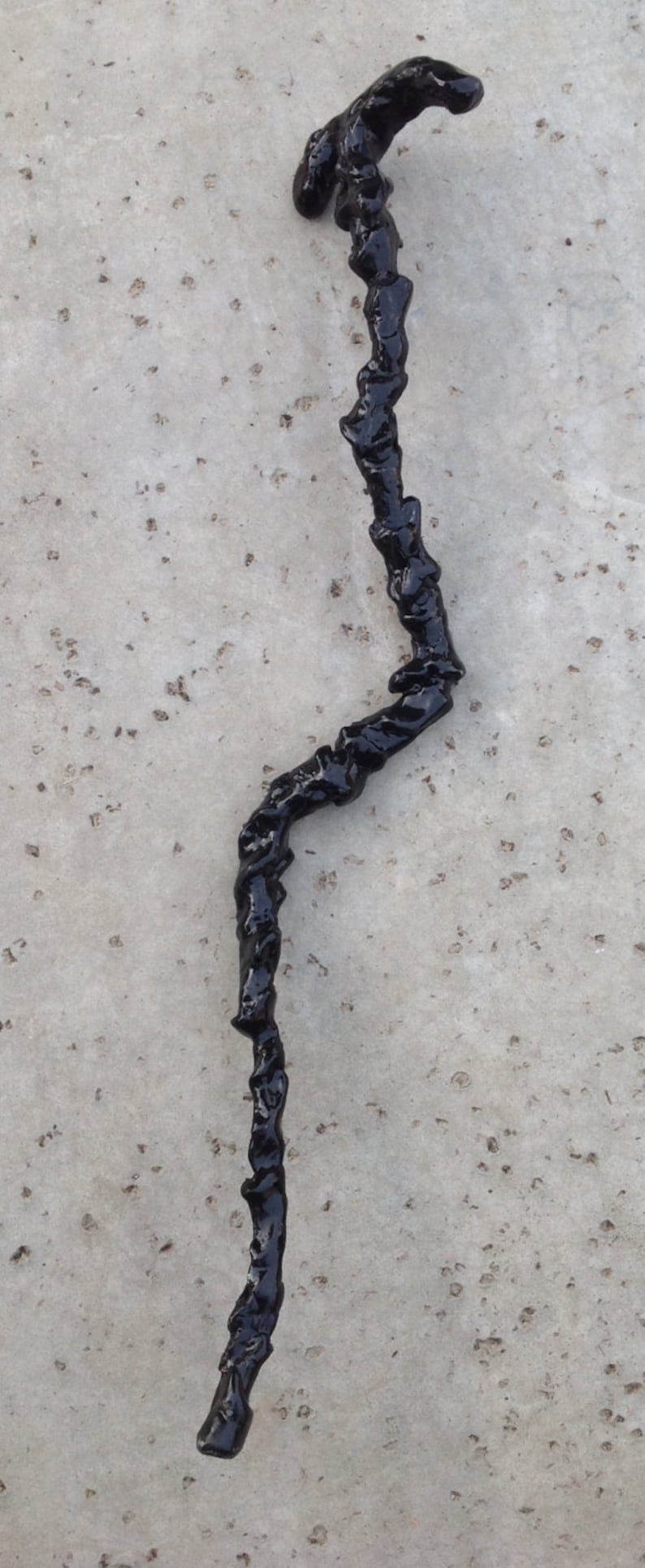May include: A black, twisted, resin stick with a rough, textured surface.