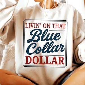 May include: Cream-colored sweatshirt with a rectangular graphic. The graphic features the text "LIVIN' ON THAT" in red, "Blue Collar" in dark blue, and "DOLLAR" in red, all within a black border.