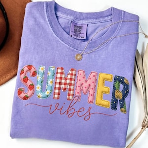 Puede incluir: Una camiseta lila Comfort Colors con las palabras "SUMMER vibes" en letras coloridas y texturizadas. Las letras están decoradas con fresas, margaritas, cuadros vichy, lunares, piñas y tela amarilla.