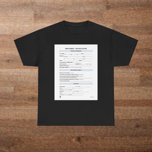 Peut inclure: T-shirt noir avec une impression d'un formulaire de demande d'emploi. Le formulaire comprend des champs pour les informations personnelles, l'éligibilité à l'emploi et les détails de l'éducation. Le t-shirt est présenté sur une surface en bois.