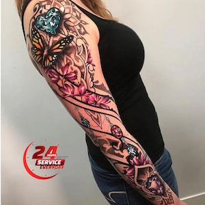 Puede incluir: Diseño de tatuaje colorido en un brazo con una mariposa, una gema en forma de corazón y elementos florales. El tatuaje incorpora tonos de azul, naranja, rosa y morado, con detalles intrincados y sombreado. El diseño se extiende desde el hombro hasta la muñeca.