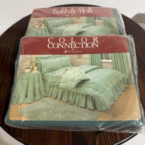 May include: Two sealed packages of bedding sets. Each package features a mint green comforter, pillowcases, sheets, and a bed skirt. The packaging reads "COLOR CONNECTION" in white text on a maroon background.