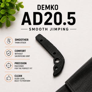 Puede incluir: Un espaciador trasero negro texturizado para cuchillo Demko AD20.5 con jimping suave. La imagen incluye el texto: DEMKO AD20.5 SMOOTH JIMPING, junto con iconos y etiquetas para las características de rendimiento de suavidad y precisión.