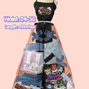 May include: A black crop top with a floral "Daisy Berry" design paired with patchwork denim pants. The pants feature various denim patches, text, and cartoon graphics. Waist: 24-38 inches. Length: 42 inches.