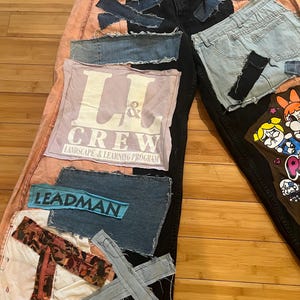 May include: Custom patchwork jeans with a unique design. The jeans feature black, pink, and light blue denim patches, with visible stitching and raw edges. Patches include the text "L & CREW" and "LEADMAN".
