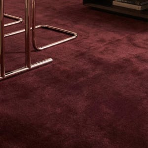 Puede incluir: Una alfombra de color burdeos intenso con una textura suave y afelpada que cubre el suelo. El texto Shadleom Rugs está superpuesto en la imagen. La alfombra se sitúa bajo una mesa negra con patas de color cobre metálico y una mesa baja.