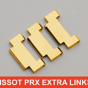 Peut inclure: Trois maillons supplémentaires Tissot PRX dorés. Chaque maillon a un centre rectangulaire avec une extrémité en forme de T. Les maillons sont sur un fond gris. Le texte "TISSOT PRX EXTRA LINKS" est dans un encadré rouge en bas.